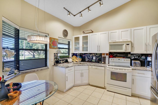 kitchen with decorative backsplash, white appliances, light tile patterned floors, white cabinetry, and hanging light fixtures