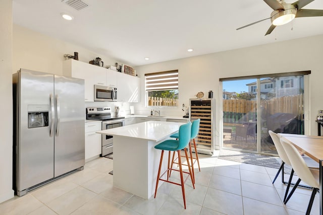 kitchen featuring appliances with stainless steel finishes, white cabinetry, beverage cooler, and light tile patterned flooring