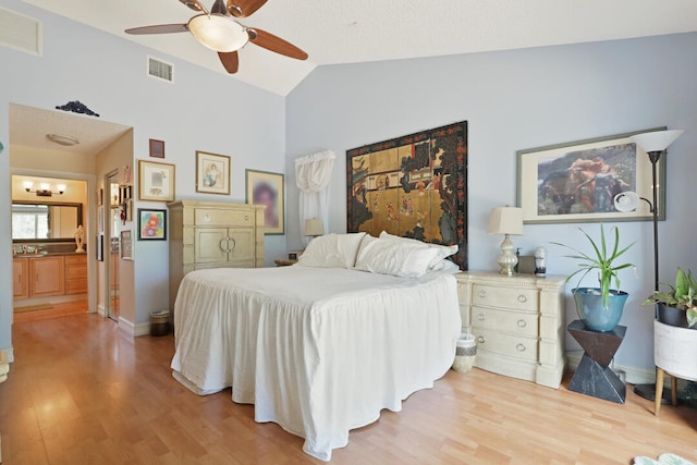 bedroom featuring light hardwood / wood-style floors, vaulted ceiling, ceiling fan, and ensuite bathroom