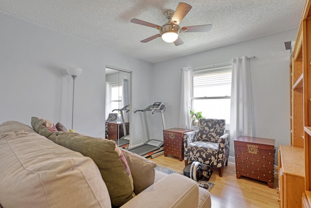 living room featuring ceiling fan, a textured ceiling, and light hardwood / wood-style flooring