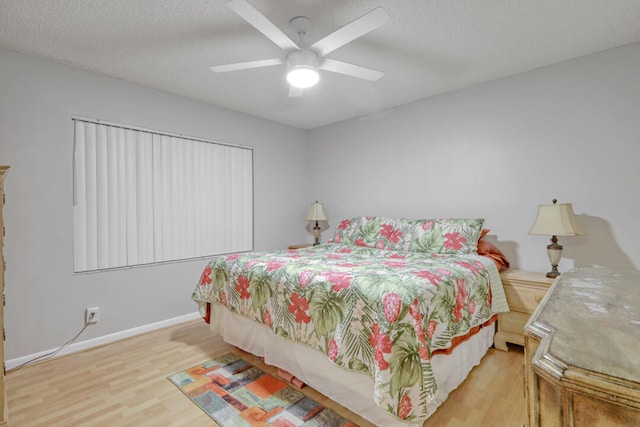 bedroom featuring ceiling fan, light hardwood / wood-style flooring, and a textured ceiling