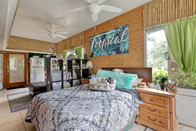 bedroom featuring white refrigerator, ceiling fan, wooden walls, and light tile patterned flooring