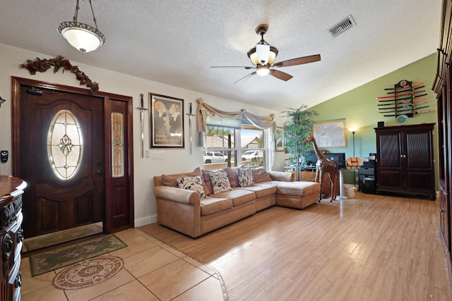 entrance foyer with a textured ceiling, ceiling fan, lofted ceiling, and light wood-type flooring