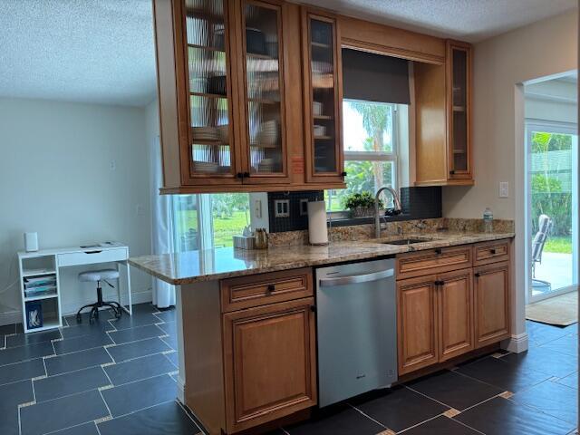 kitchen featuring sink, a textured ceiling, light stone countertops, and dishwasher