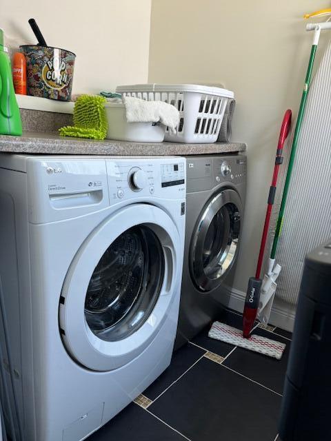 washroom featuring washing machine and clothes dryer and dark tile patterned floors