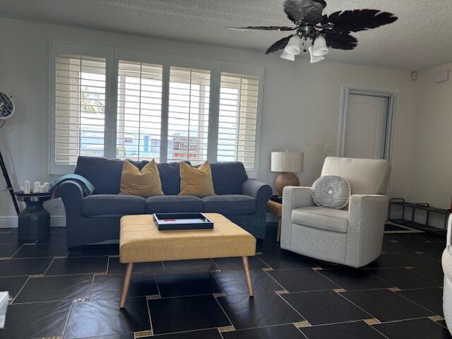 living room with ceiling fan and a textured ceiling