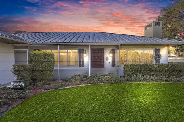 back house at dusk with a lawn