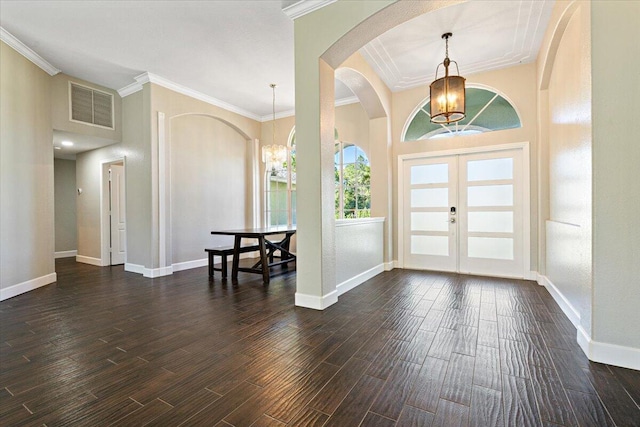 foyer entrance featuring an inviting chandelier, dark hardwood / wood-style flooring, crown molding, and french doors