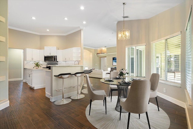 dining area with ornamental molding, dark wood-type flooring, and an inviting chandelier