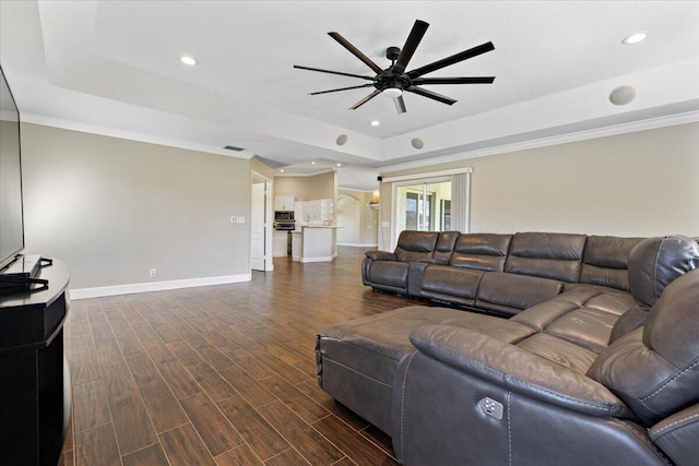 living room with ceiling fan, crown molding, dark wood-type flooring, and a tray ceiling