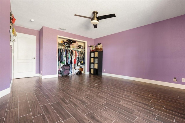 unfurnished bedroom featuring a textured ceiling, a closet, dark wood-type flooring, and ceiling fan