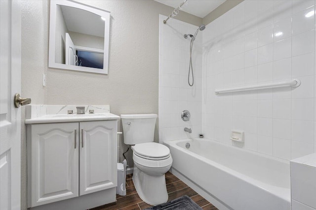 full bathroom with hardwood / wood-style floors, vanity, tiled shower / bath combo, and toilet