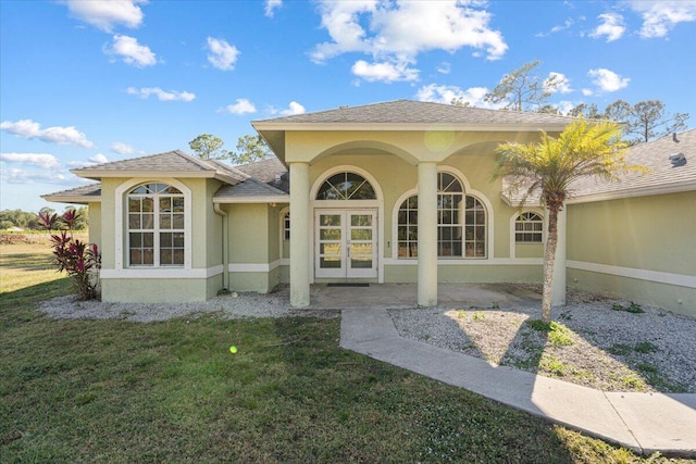 entrance to property with french doors and a lawn