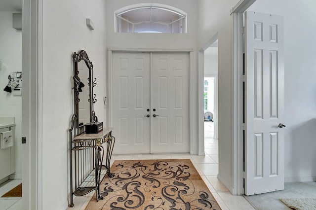 foyer featuring light tile patterned floors and high vaulted ceiling