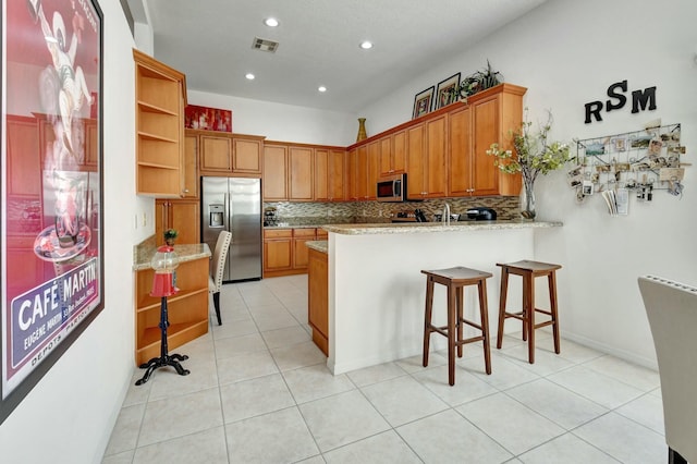 kitchen featuring kitchen peninsula, stainless steel appliances, light tile patterned floors, and tasteful backsplash