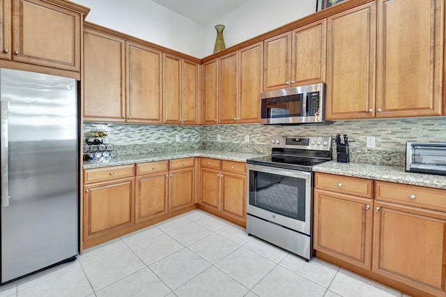 kitchen with backsplash, light stone counters, light tile patterned floors, and stainless steel appliances