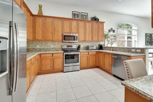 kitchen featuring sink, decorative backsplash, light stone countertops, light tile patterned floors, and appliances with stainless steel finishes