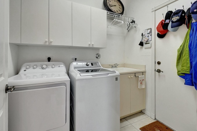 laundry room featuring washing machine and clothes dryer, sink, light tile patterned flooring, and cabinets