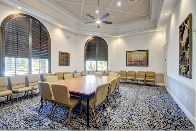 carpeted dining space with a high ceiling, ceiling fan, crown molding, and coffered ceiling