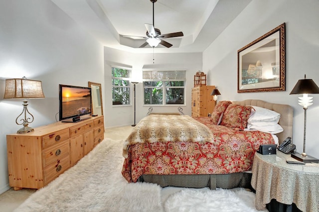 bedroom with ceiling fan, a raised ceiling, and light carpet