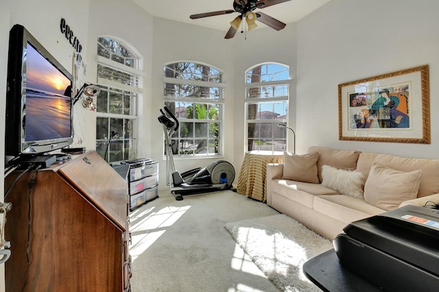 carpeted living room featuring ceiling fan and a high ceiling