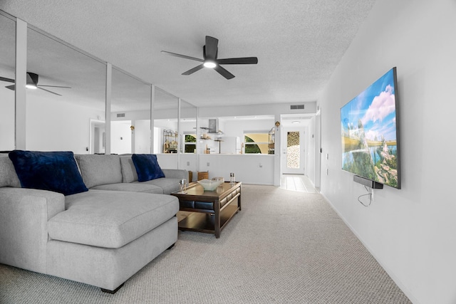 living room with a textured ceiling, ceiling fan, and carpet