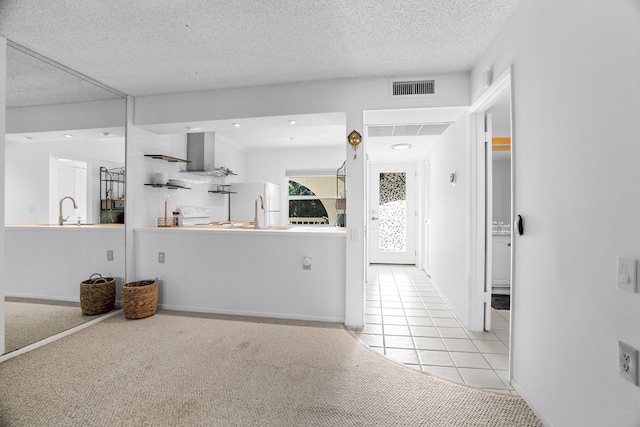 kitchen with white refrigerator, a textured ceiling, light carpet, and wall chimney range hood