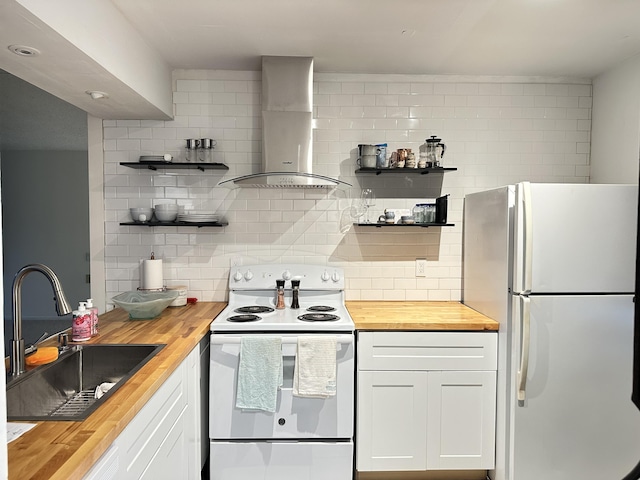 kitchen with white appliances, wooden counters, wall chimney exhaust hood, sink, and white cabinetry