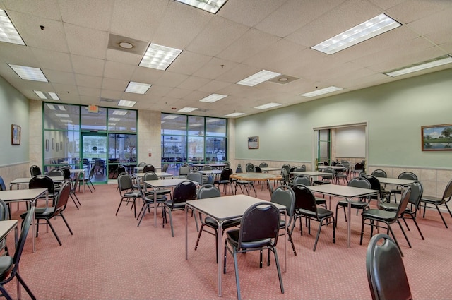 carpeted dining area with a drop ceiling