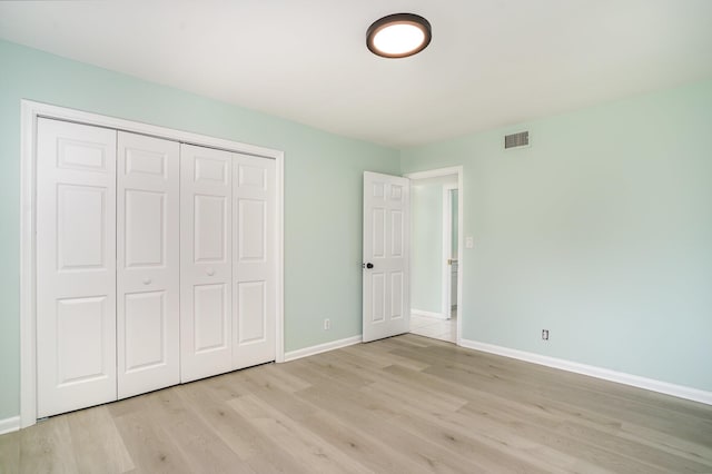 unfurnished bedroom with light wood-type flooring and a closet