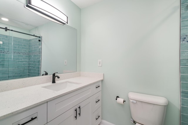 bathroom with vanity, toilet, and a shower with door