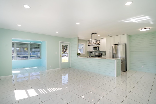 kitchen featuring white cabinetry, hanging light fixtures, stainless steel appliances, kitchen peninsula, and light tile patterned flooring