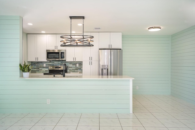 kitchen featuring white cabinets, appliances with stainless steel finishes, hanging light fixtures, and sink