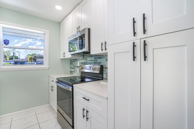 kitchen featuring white cabinets, appliances with stainless steel finishes, backsplash, and light tile patterned floors