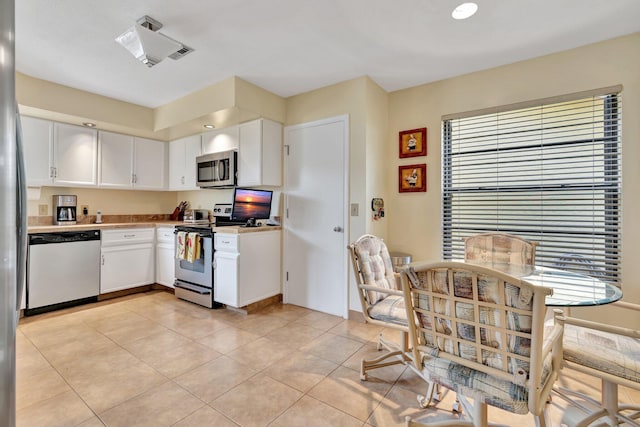 kitchen with white cabinets, appliances with stainless steel finishes, plenty of natural light, and light tile patterned flooring