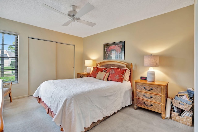 carpeted bedroom with ceiling fan, a textured ceiling, and a closet