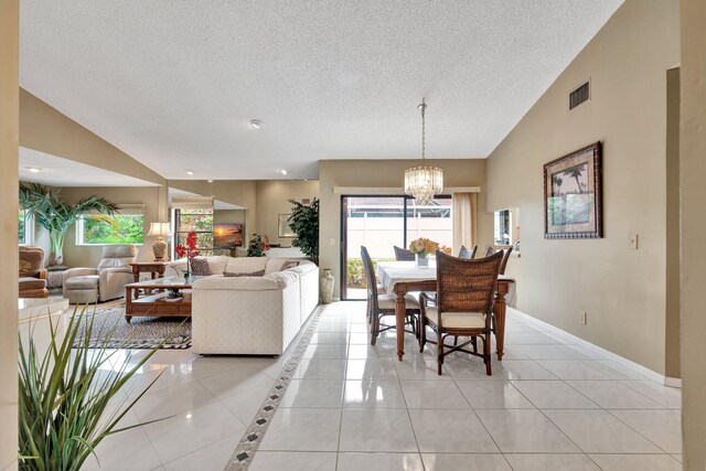 living room with a notable chandelier, light tile patterned flooring, a textured ceiling, and high vaulted ceiling