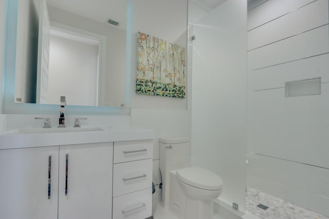 bathroom with vanity, toilet, and tiled shower