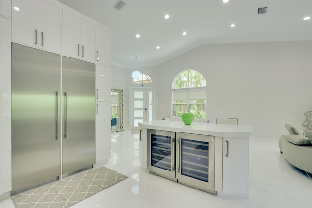 bar with pendant lighting, white cabinetry, built in refrigerator, and crown molding