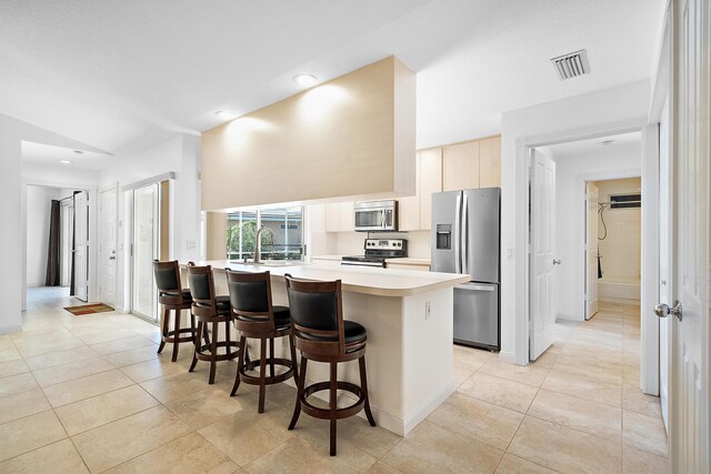 kitchen featuring a kitchen breakfast bar, sink, light tile patterned floors, and stainless steel appliances