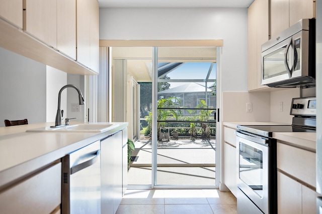 kitchen with sink, light tile patterned floors, and stainless steel appliances