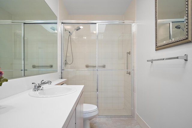 bathroom featuring tile patterned flooring, vanity, a shower with shower door, and toilet