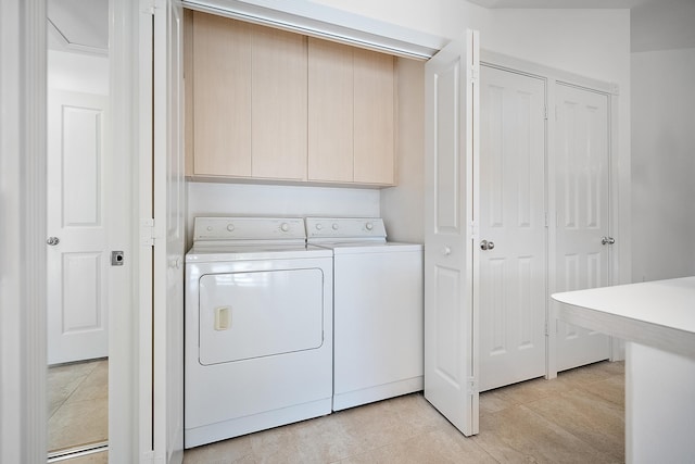 clothes washing area featuring washer and clothes dryer, light tile patterned floors, and cabinets