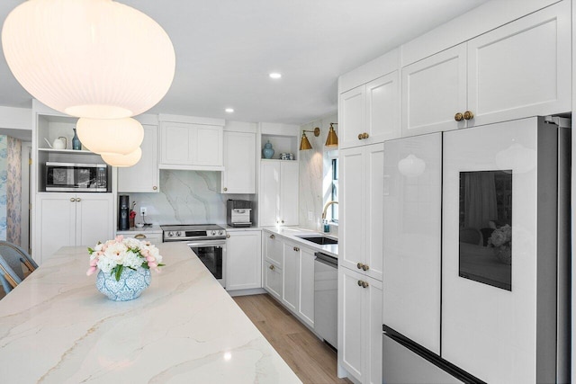 kitchen with white cabinetry, light wood-type flooring, stainless steel appliances, sink, and light stone counters