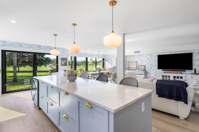 kitchen featuring light hardwood / wood-style flooring, hanging light fixtures, a center island, and beverage cooler