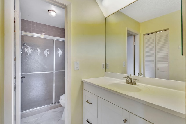 bathroom with tile patterned floors, vanity, toilet, and a shower with shower door