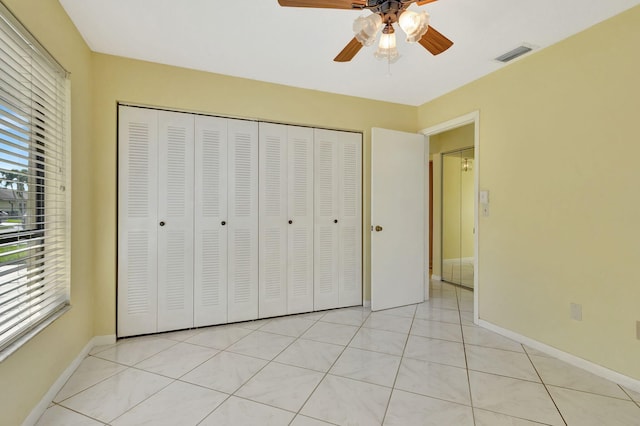 unfurnished bedroom featuring light tile patterned floors, multiple windows, and ceiling fan