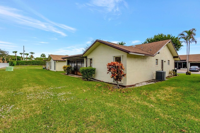 view of side of home featuring a lawn, central AC, and a sunroom