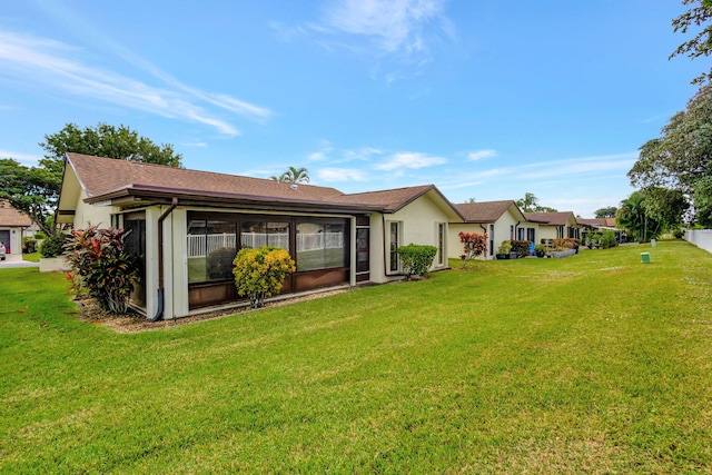 back of property with a lawn and a sunroom