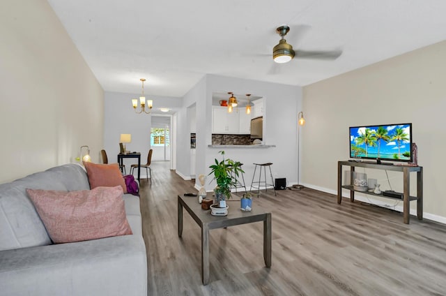 living room featuring light hardwood / wood-style floors and ceiling fan with notable chandelier